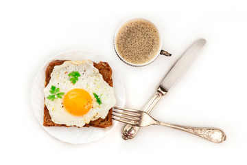 An egg cooked sunny side up on a toast with coffee, shot from the top on a white background with copy space