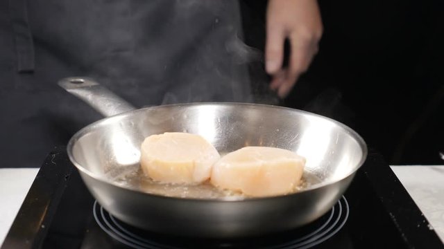 Food concept. Professional chef in gloves frying scallops in slow motion. Clouds of white steam above. Close up. hd