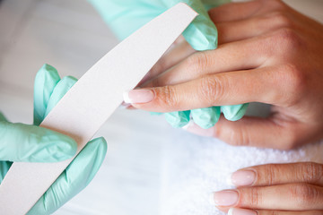 Manicure. Skillful master of manicure holding file in her hands while working in her beauty salon