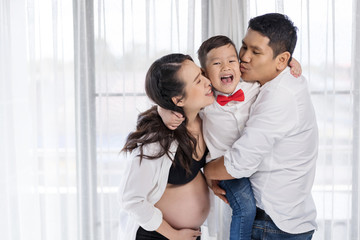 Obraz premium happy family concept, pregnant mother and father kissing boy