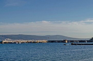 Obraz premium Seascape of pier with cross at end for fishing boat in the Black Sea and Balkan mountain with Cape Emine near ancient city Nessebar, Bulgaria, Europe
