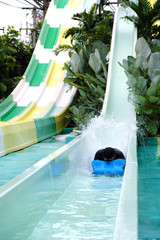 Head of man coming down on the slide make the water splashing in the aqua park , water park resort. Summer Vacation.