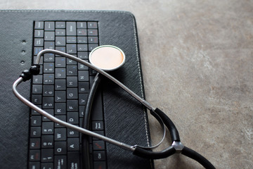Stethoscope on black keyboard of laptop or electronic tablet. E-health and mobile healthcare concept. Computer diagnostic and repair concept. 