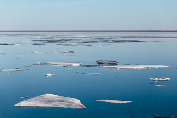 White and black ice floes on blue water surface. Spring background