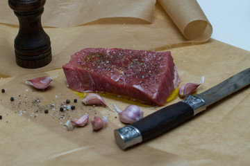 Extreme Close Up view of a Hand Seasoning Cooked piece of Meat in a Bright Light. Chef Accompanying Steak with Garlic, Rosemary, Pepper, Salt. Delicious, Modern Cuisine, Exclusive Recipe. 