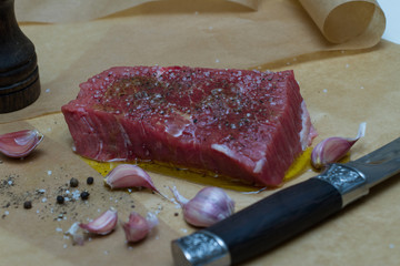 Extreme Close Up view of a Hand Seasoning Cooked piece of Meat in a Bright Light. Chef Accompanying Steak with Garlic, Rosemary, Pepper, Salt. Delicious, Modern Cuisine, Exclusive Recipe. 