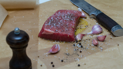 Extreme Close Up view of a Hand Seasoning Cooked piece of Meat in a Bright Light. Chef Accompanying Steak with Garlic, Rosemary, Pepper, Salt. Delicious, Modern Cuisine, Exclusive Recipe. 