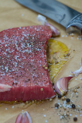 Extreme Close Up view of a Hand Seasoning Cooked piece of Meat in a Bright Light. Chef Accompanying Steak with Garlic, Rosemary, Pepper, Salt. Delicious, Modern Cuisine, Exclusive Recipe. 