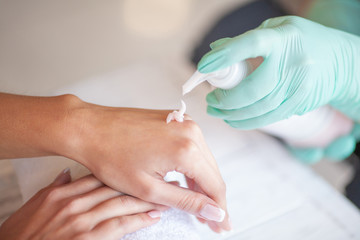 Disinfection hands before manicure in the salon closeup. Beautician is disinfecting client's with desinfectant