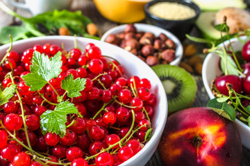 Red currant on table with food. Healthy super foods for breakfast, bowls with organic fresh fruits and nuts. Vegetarian diet concept.