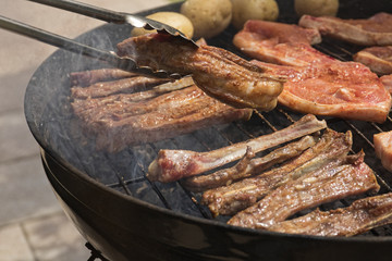 tasty lamb meat being turned on a bbq or braai