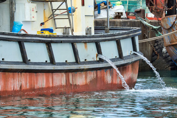 Fototapeta na wymiar Water being pumped from a fishing vessel while in harbour