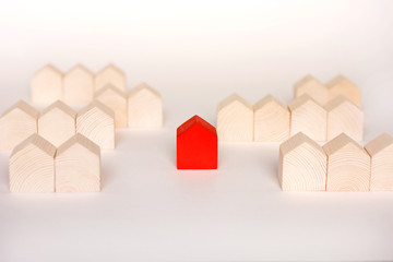 Rows of wooden houses with single red house in center on white background