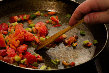 morning omelet with wooden spatula on big cast iron pan on black background