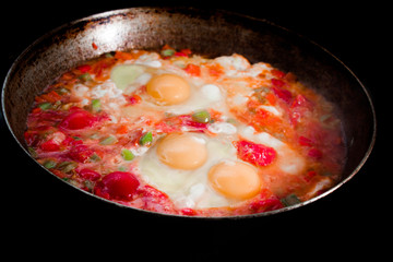 morning omelet on big cast iron pan on black background