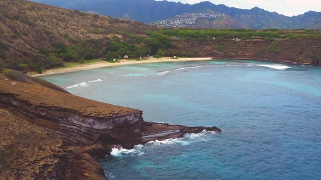 Aerials shots of Hanauma Bay, Oahu, Hawaii. Deep blue Pacific Ocean and coral reefs meet the yellow sand beach and rocky shores. Koolau mountains and Hawaii Kai in the background. 