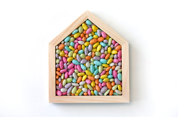 Wooden house frame with sweet candies inside on white background