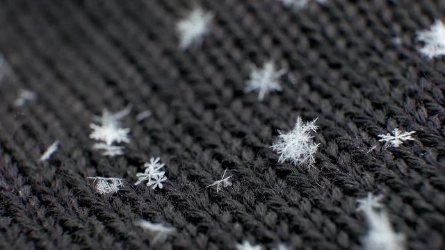 Macro Snowflake on black woolen mittens. UHD 4K video. Snowflake structure