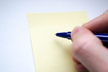 A simple orange pencil in the right hand above the yellow sheet for notes.