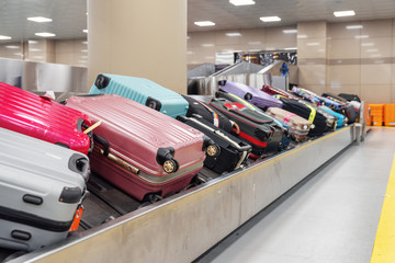 Pink, blue and violet suitcases on luggage conveyor belt