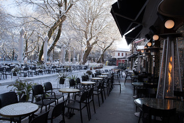 coffees shops tables chairs in the snow ice winter season trees road in Ioannina city Greece