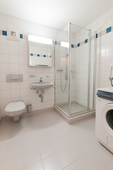 modern bathroom in an empty and refurbished apartment with sink shower and washing machine and toilet