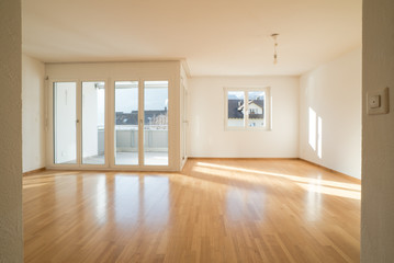 Fototapeta na wymiar bright new living room in an empty apartment with french doors and parquet wooden floors