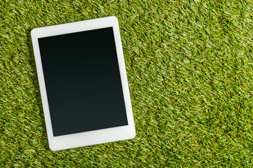 top view of digital tablet with blank screen on green grass, energy efficiency concept