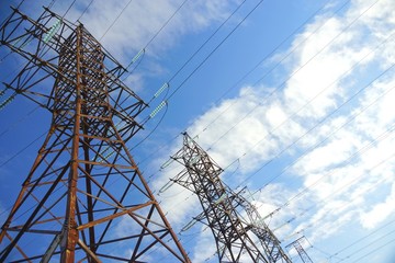 Power transmission line pylons with threatening blue clouds background