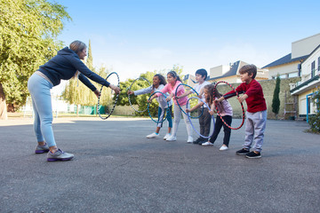 Sportlehrer zeigt Kindern Übung mit Reifen