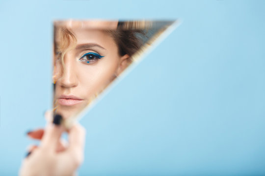 Fototapeta Woman looking at her self reflected in a mirror, selfie, vanity, conceit, ego, digital narcissism concept minimal flat design. An illusion, beautiful girl with a mirror in her hands