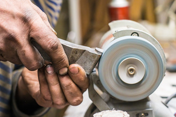 sharpener are grinding lathe tool on sharpening green silicide carbide stone in his workshop