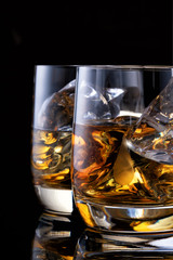 two glasses of whiskey on the table with a bottle