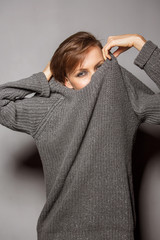 Young woman wearing sweater isolated over grey