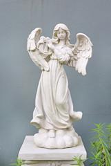 Beautiful angel statue against gray wall background.