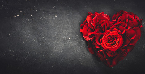 Heart-shaped red roses on stone background.