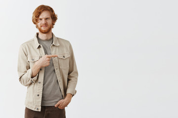 Studio shot of unimpressed picky and displeased attractive male client with red hair and beard...