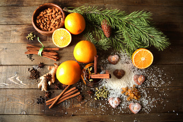 Christmas still life composition with mulled wine, heart-shaped cookies, coconut snow, nuts, oranges and spices on a wooden background with a fir branch. Flat lay, top view.