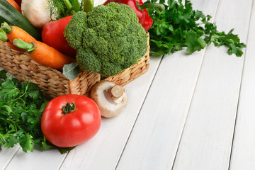 Wicker basket with vegetable assortment on wooden table