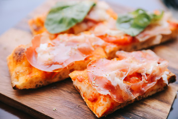 Pizza with parma ham salad rocket and parmesan on dark wooden background close up. Italian food