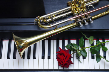 Piano keyboard, trumpet and red rose. Close-up