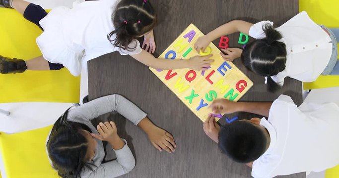 Flat lay scene video of Asian students playing colorful alphabet letters toy together, concept for English class.