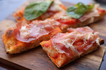 Pizza with parma ham salad rocket and parmesan on dark wooden background close up. Italian food