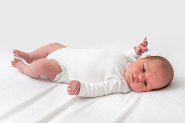 Newborn baby is lying on back on white blanket