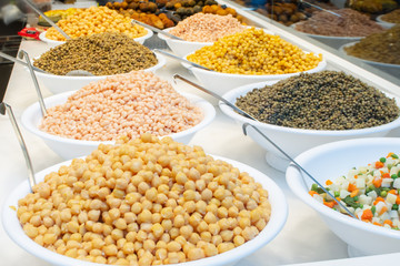 Variety of different types of cooked beans, lentil and peas sold on food market in barcelona in bowls