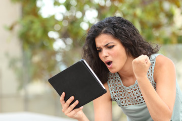 Excited girl watching media content on a tablet in a park
