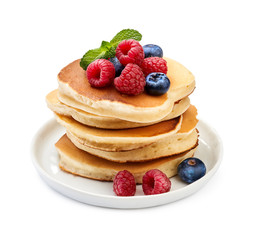 Stack of delicious pancakes with berries and mint leaf on plate isolated on white.