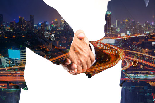 Businessman greeting Shakehand deal with Modern City shining at Night
