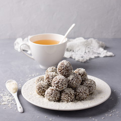 Homemade raw date candies with coconut chips on a gray background. delicious healthy dessert