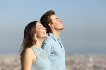 Happy couple breathing fresh air with urban background